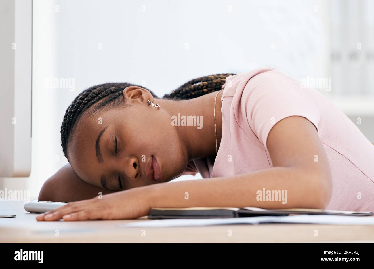Burnout, sleep and black woman tired from stress, anxiety and problem at a desk in an office at work. Young African corporate worker sleeping at a Stock Photo