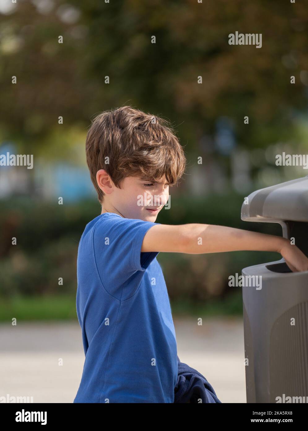 Caucasian kid 9 year old try to throw trash in public trashcan. Concept