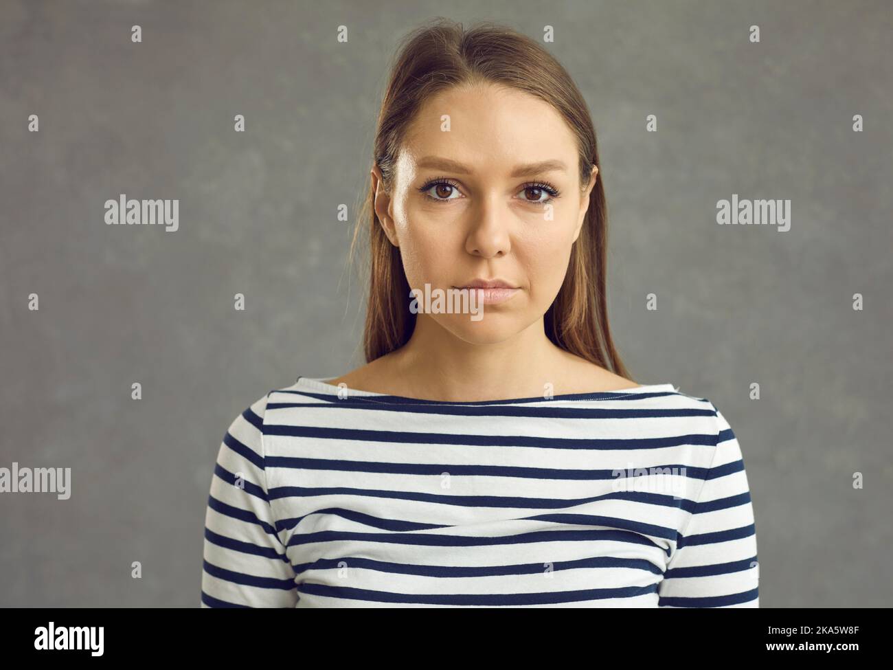 Studio portrait of young woman looking at camera with serious unemotional expression Stock Photo
