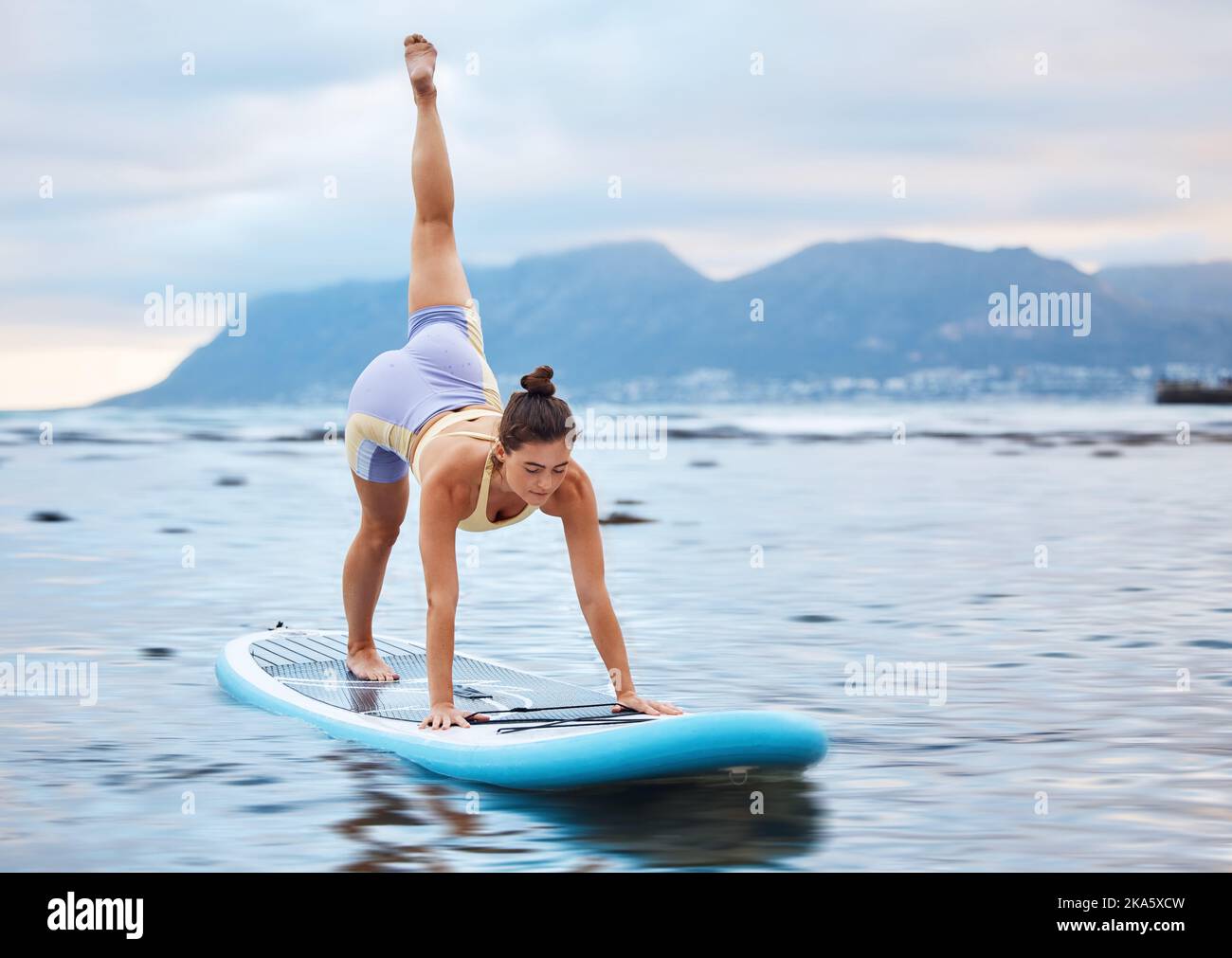 Surfer, flexible and woman on surfboard at a beach training, workout