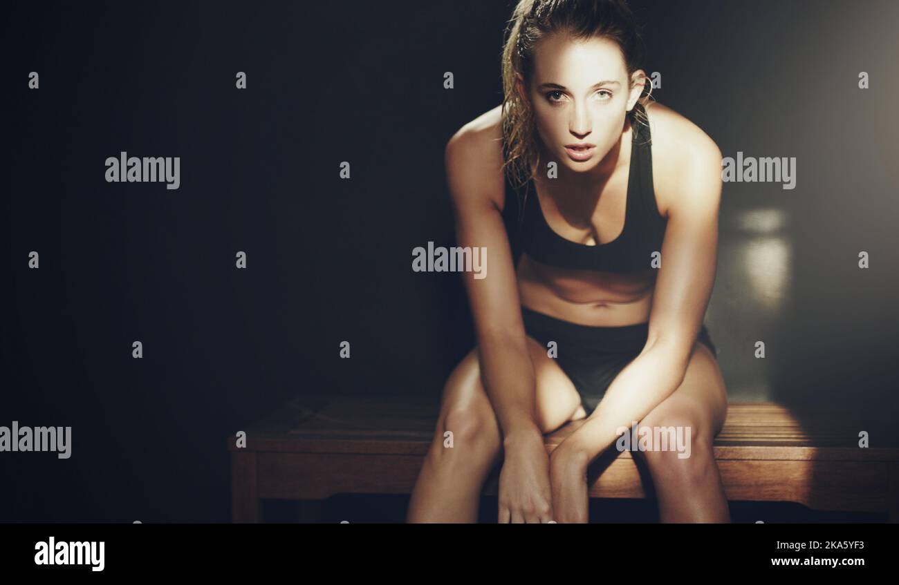 Focusing herself for the workout ahead. Cropped portrait of an attractive young woman sitting a gym locker room. Stock Photo