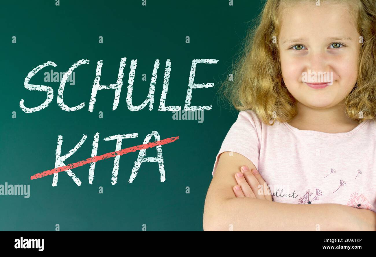Pupil in front of a blackboard with the German words: Schule statt Kita (school instead of daycare) Stock Photo