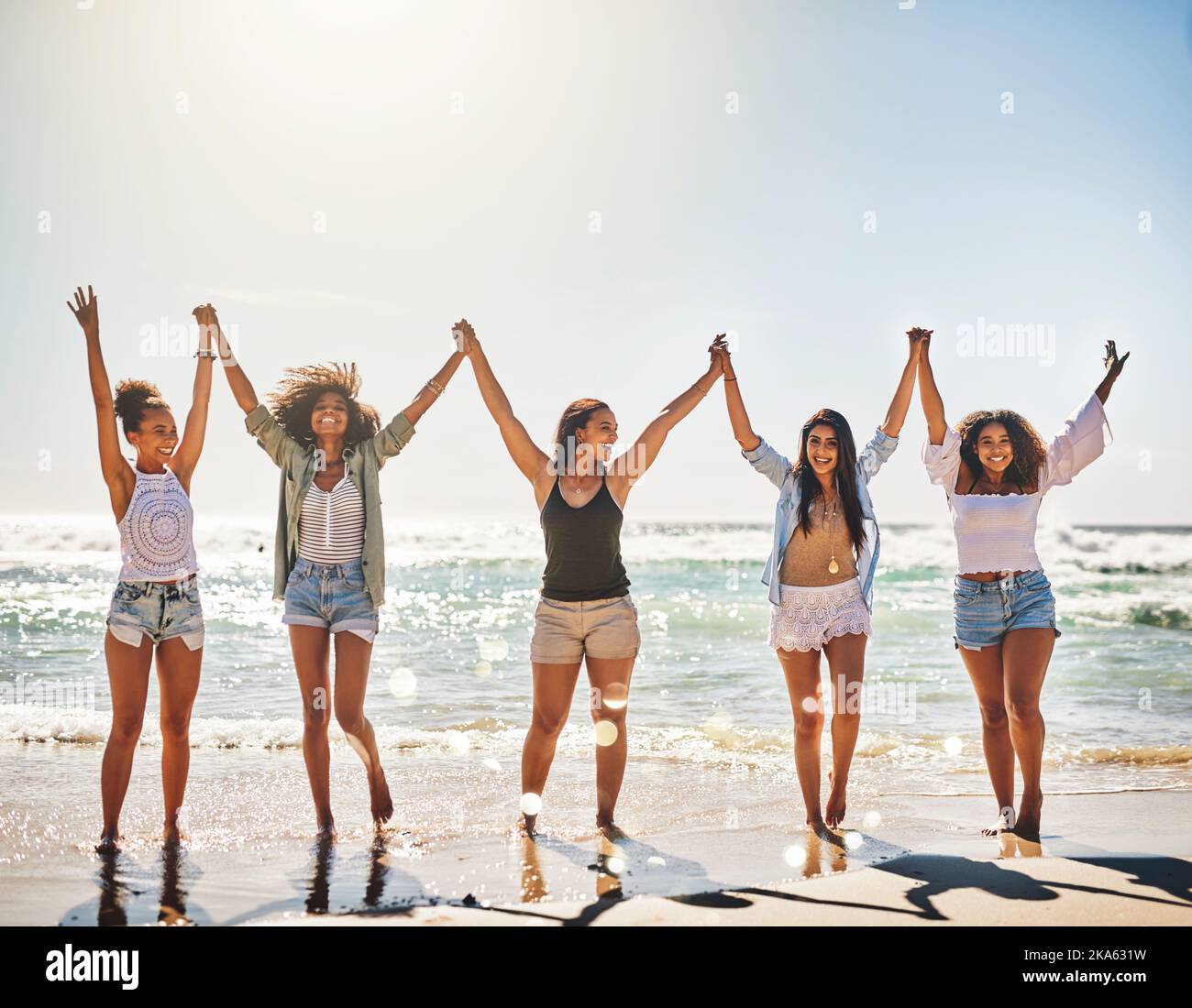 Bring on the good times. a group of cheerful friends holding hands on the beach. Stock Photo