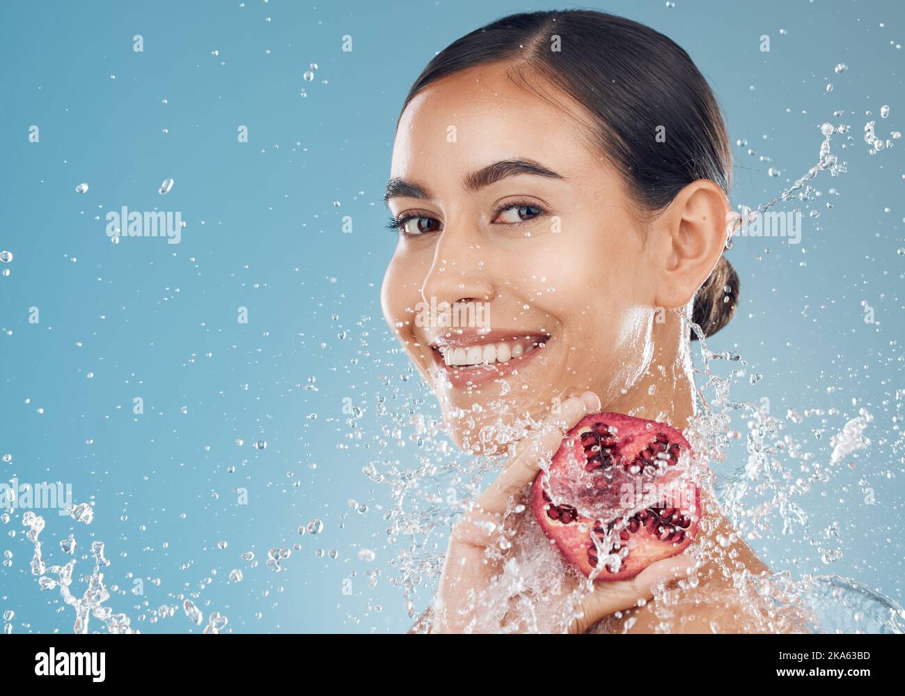 Skincare, pomegranate and healthy woman with organic skin care for fresh face on a studio background. Fruit, food and vitamin c for glowing, smooth Stock Photo