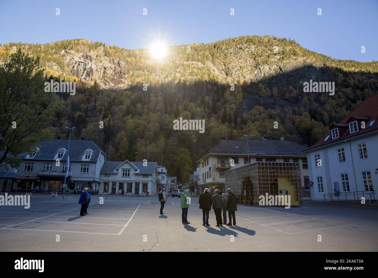 People gather at a spot illuminated by reflected sunlight in front of the town hall of Rjukan, Norway, 18 October 2013. Rjukan, known for its darkness in winter, is located in the bottom of a valley between steep mountains in Telemark County, some 150 km west of Oslo. The idea about mirrors reflecting sunshine to the town in winter was brought up already 100 years ago and only now became reallity. The mirrors will officially start operation on 31 October.  Stock Photo