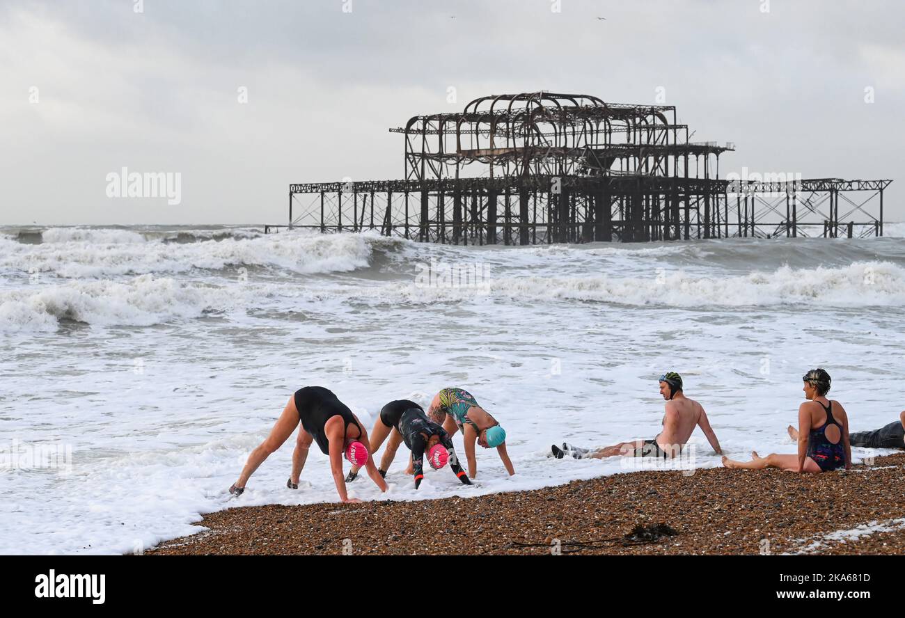 Brighton UK 1st November 2022 - Members of the iSWIM community of sea swimmers in Brighton take a bracing early morning dip near the West Pier after a night of strong winds and rain brought by Storm Claudio in the UK  . : Credit Simon Dack / Alamy Live News Stock Photo