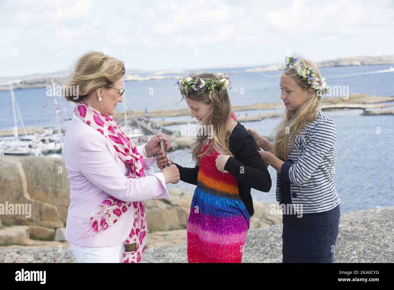 Faerder, Norway 20150627. HM Queen Sonja visits Faerder National Park at Verdens Ende on Tjoemoe. She is flying a kite with Anna Almquist and Neele Putz, both are 5th grade students at Lindhoy school. Foto: Terje Bendiksby / NTB scanpix .  Stock Photo