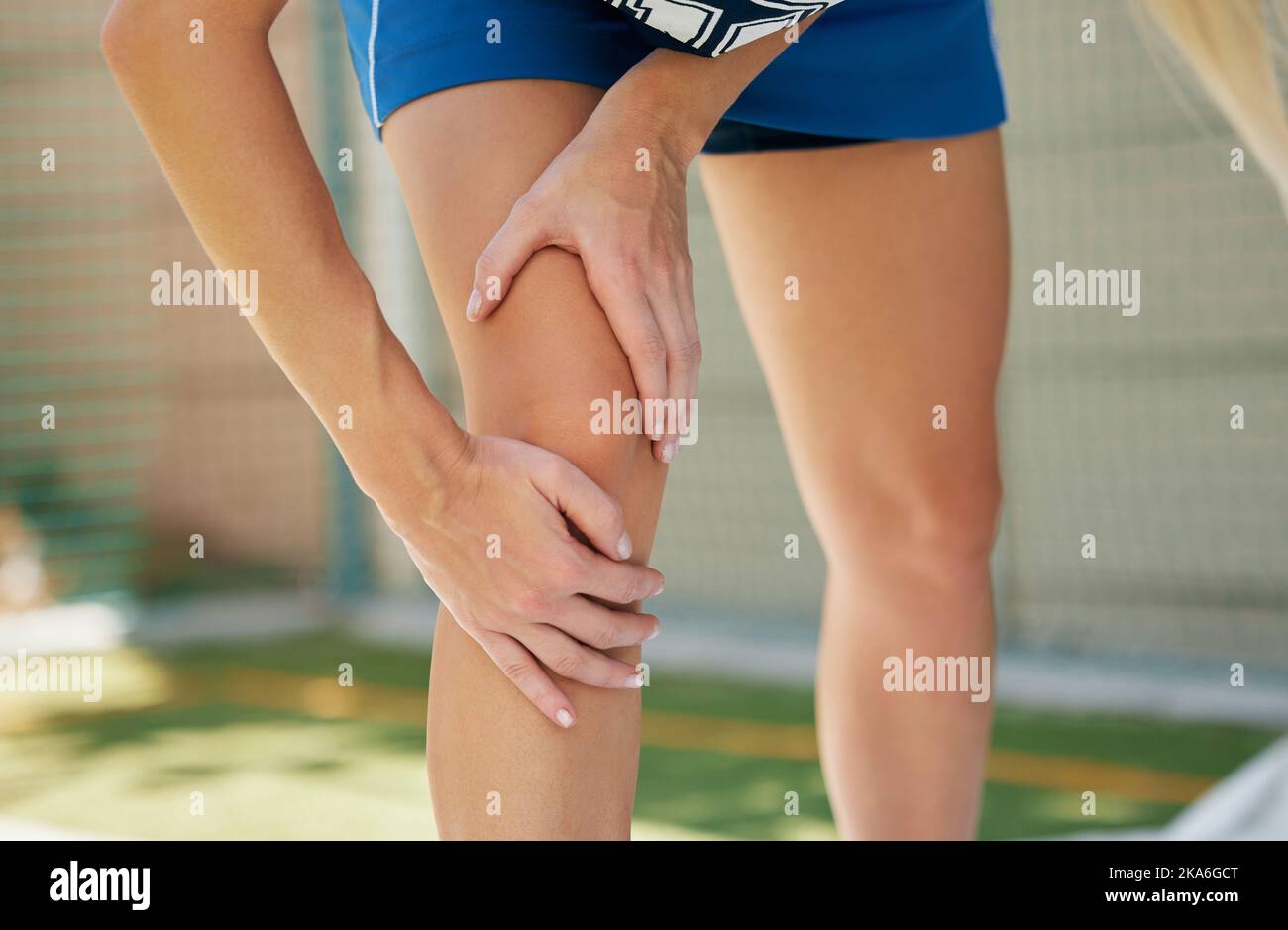Netball hands, sports muscle and woman injury with medical emergency during sport game on court. Professional athlete with pain after knee accident or Stock Photo