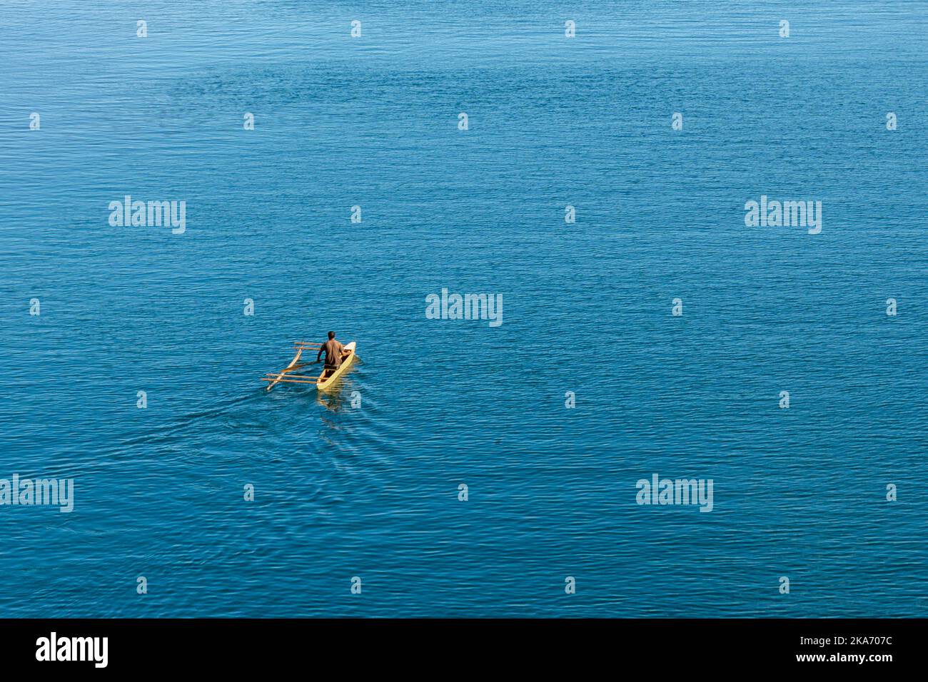 One person in traditional wooden dugout canoe fishing in Milne Bay Papua New Guinea Stock Photo