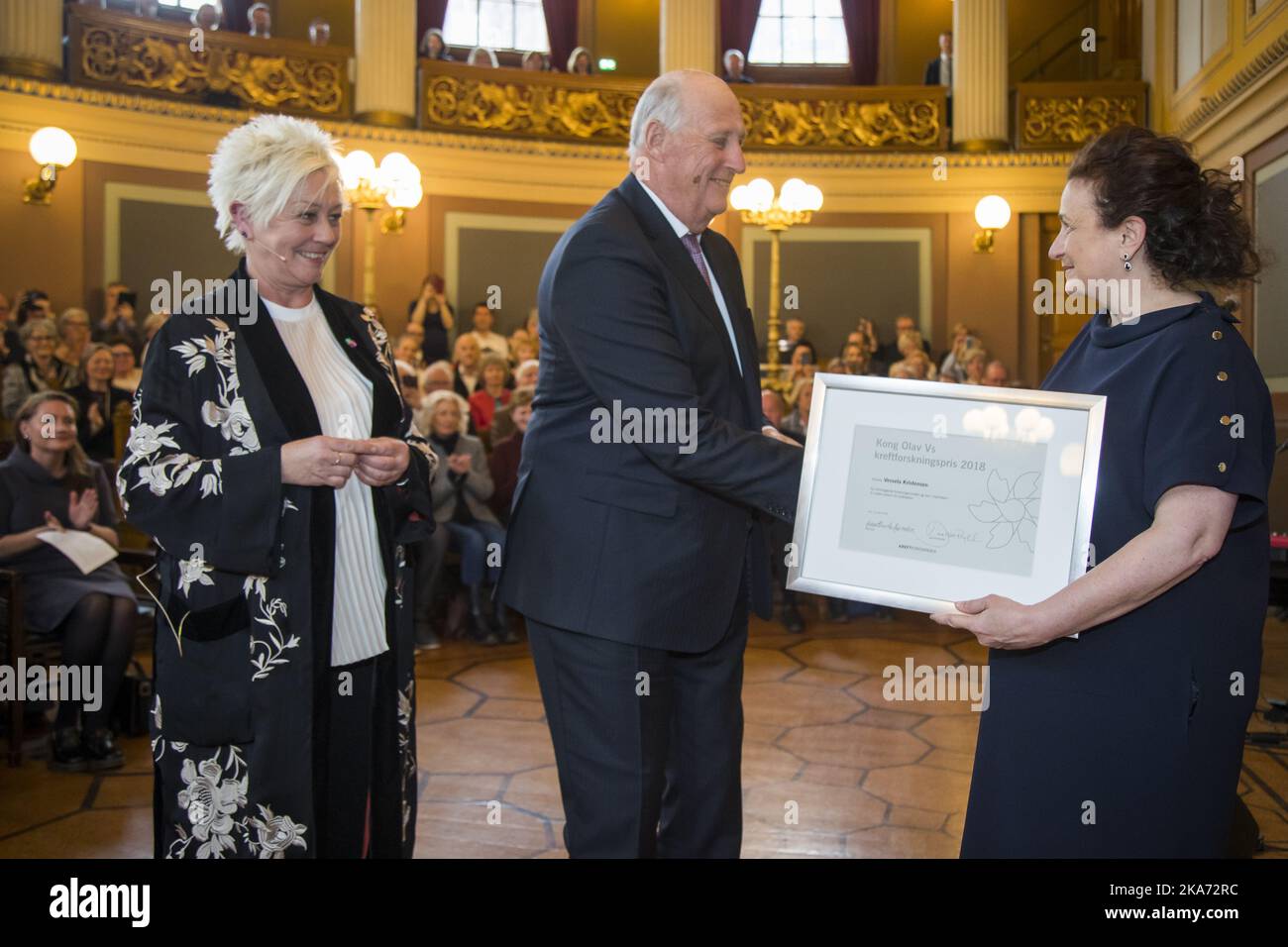 Oslo, Norway 20180416. King Harald presents Professor Vessela Kristensen (UiO) Kong Olav Vs Cancer Research Prize for 2018 at the University's Old Hall Monday. The Cancer Research Prize is awarded by the Cancer Society to researchers who have distinguished themselves through years of efforts for a better life for many people. General Secretary of the Cancer Society Anne Lise Ryel left.. Photo: Heiko Junge / NTB scanpix Stock Photo