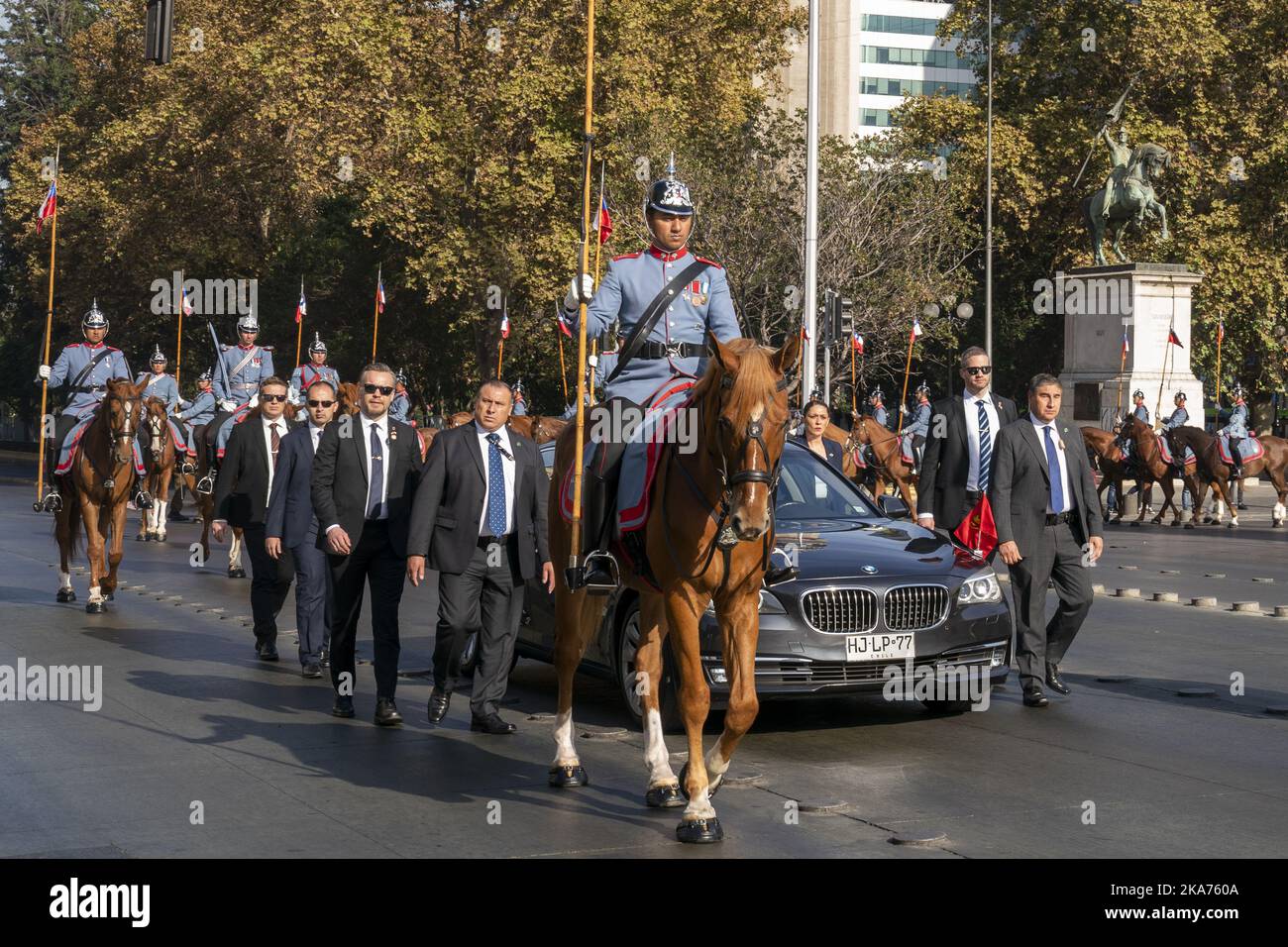 Santiago, Chile 20190326. King Harald and Queen Sonja are well protected in a BMV with running security guards and honorary horses on horseback arriving at the Bernardo O'Higgins Monument and the Presidential Palace in Santiago. The royal couple will be on a six-day state visit to Chile. Photo: Heiko Junge / NTB scanpi Stock Photo