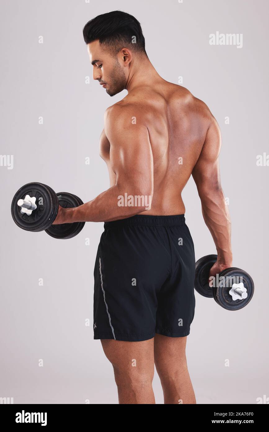 Man, working out muscle and dumbell in studio for strength training, weightlifting exercise and healthy fitness training routine. Muscular athlete Stock Photo