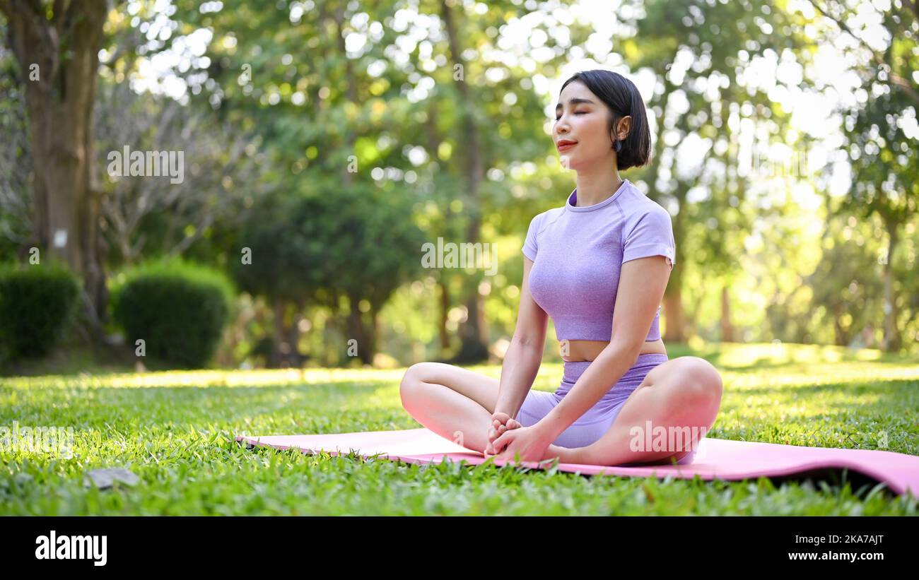 Beautiful and relaxed young Asian woman in sportswear sitting on her ...