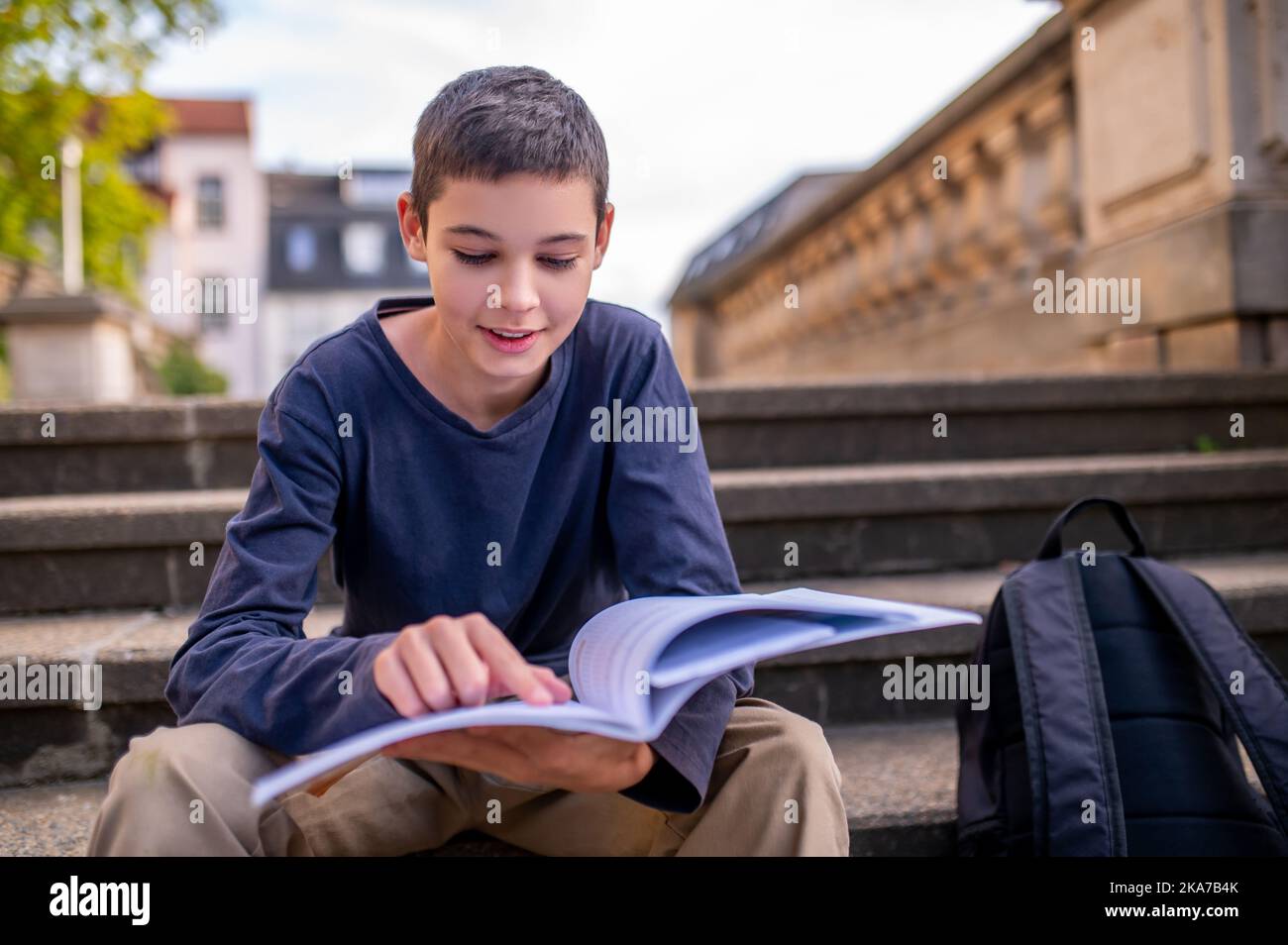 Teenage boy engrossed in reading a book Stock Photo