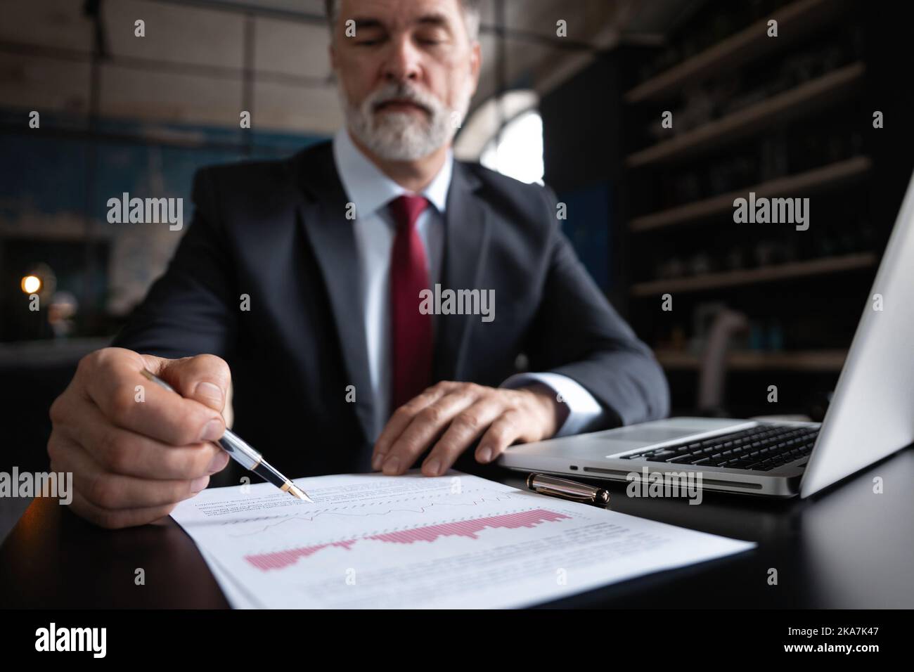 Mature businessman signs documents with a pen making the signature ...