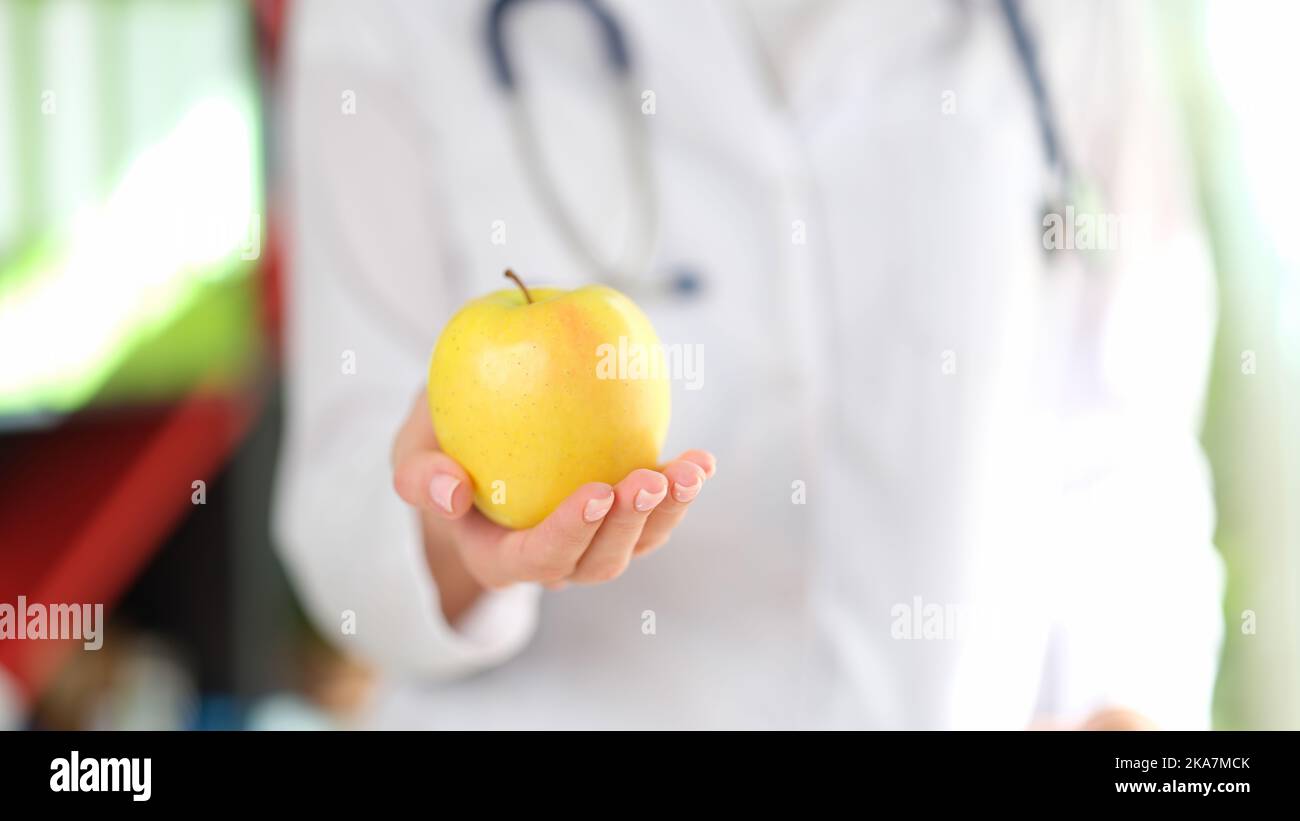 Doctor holding ripe yellow apple in hand Stock Photo
