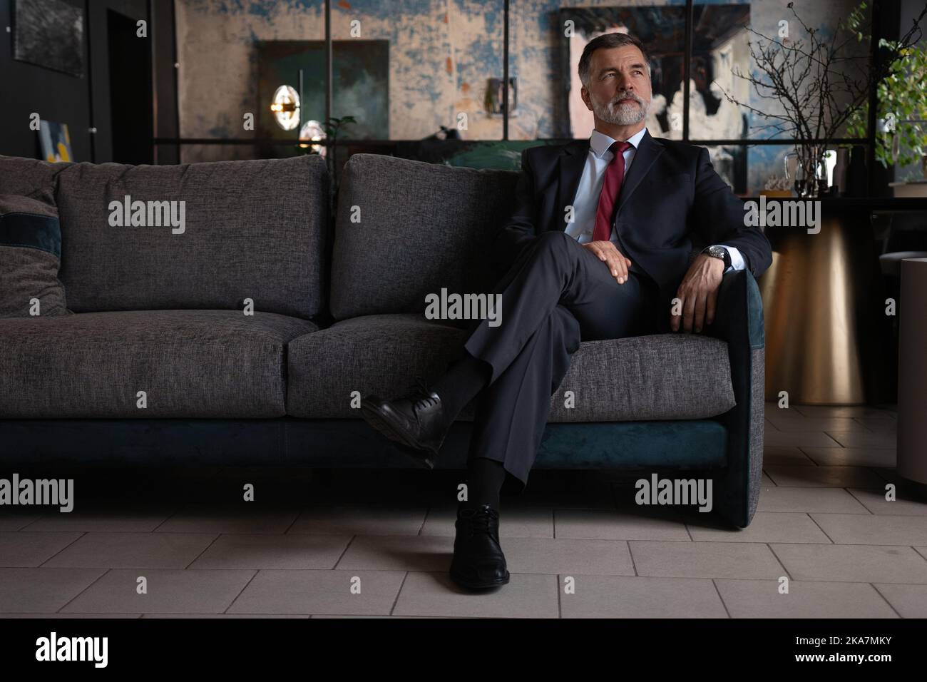 Starting new working day. Mature businessman sitting on the couch in office. Stock Photo