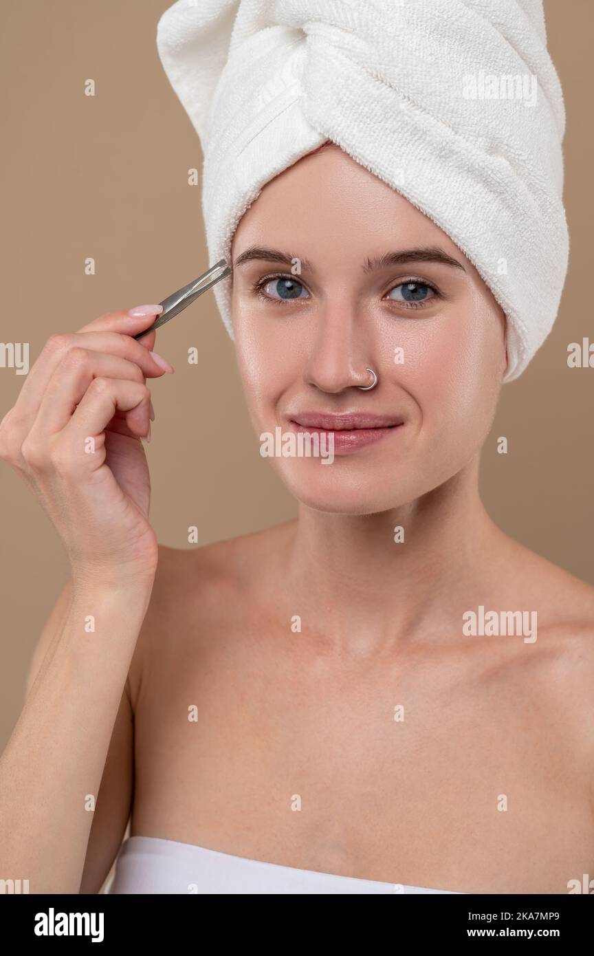 Young girl with towel on head making eyebrows Stock Photo