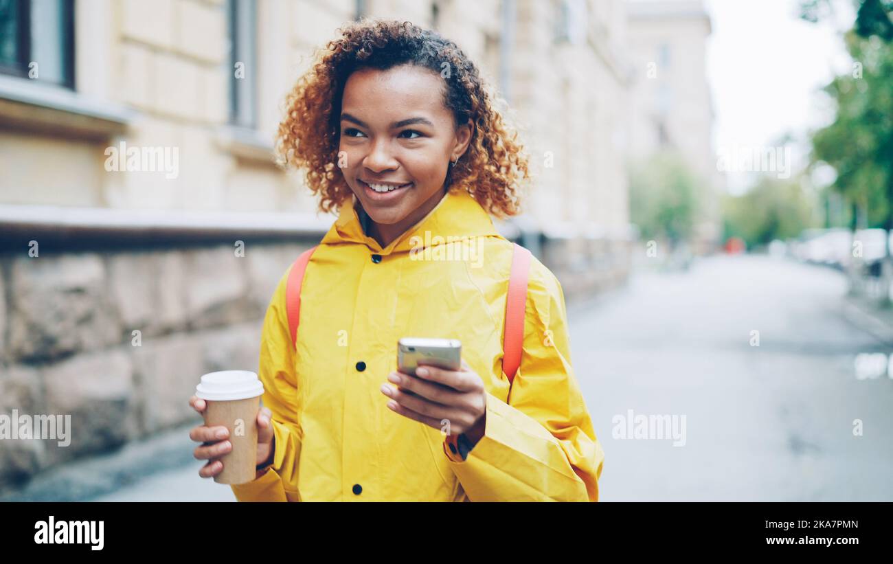 Happy African American woman is using smartphone touching screen and ...