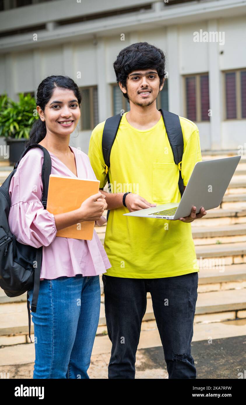 vertical shot of Happy smiling students with backpack holding laptop looking camea at college campus - concept of technology, friendship and skill Stock Photo