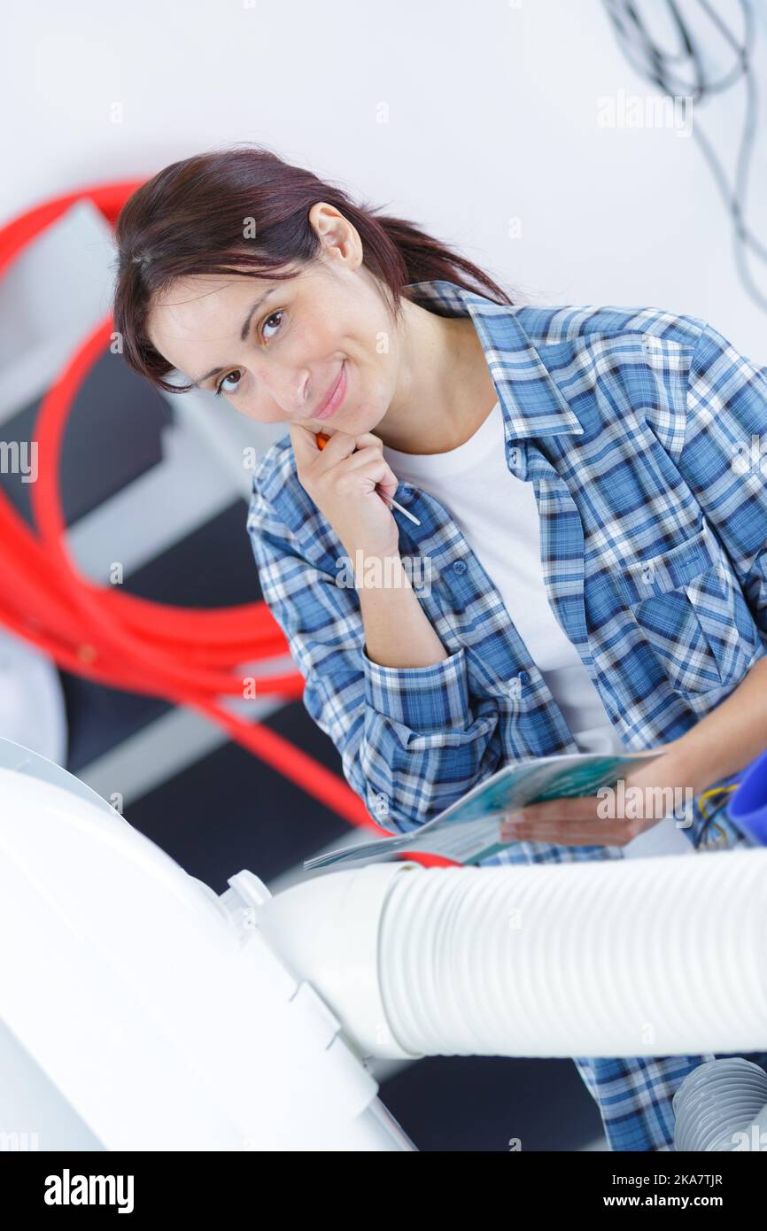 female plumber servicing central heating boiler Stock Photo