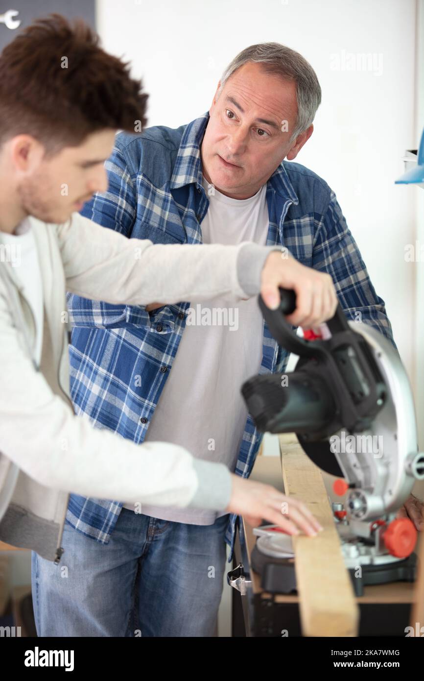 student and teacher in carpentry class using circular saw Stock Photo