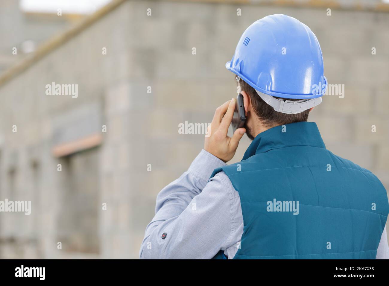 male builder foreman on building site using phone and plans Stock Photo