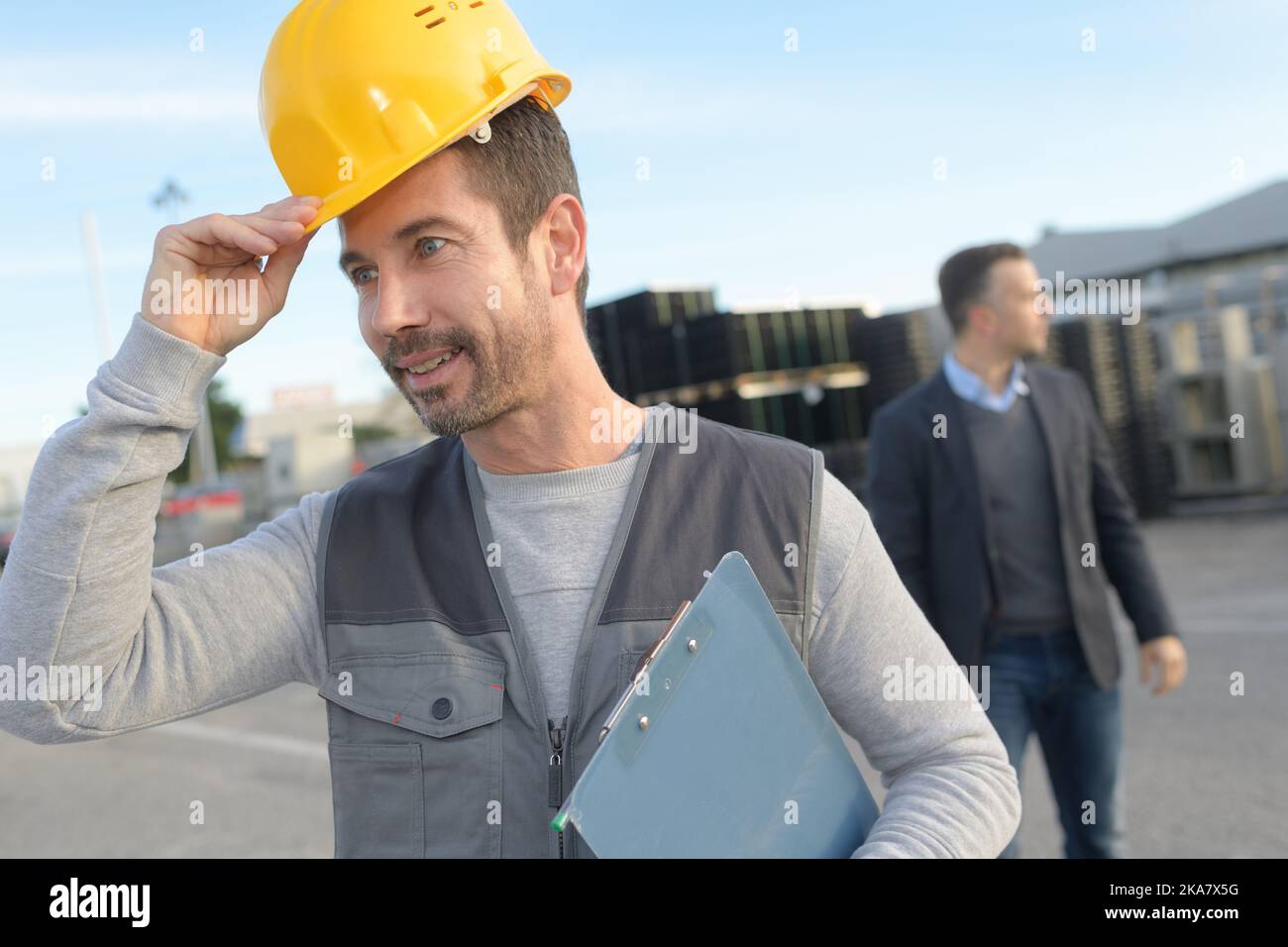 worker putting his hardhat and holding clipboard Stock Photo