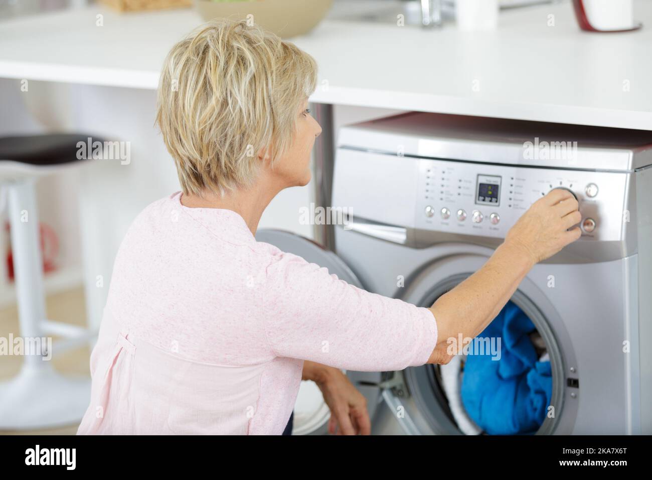 a mature woman using washing machine Stock Photo Alamy