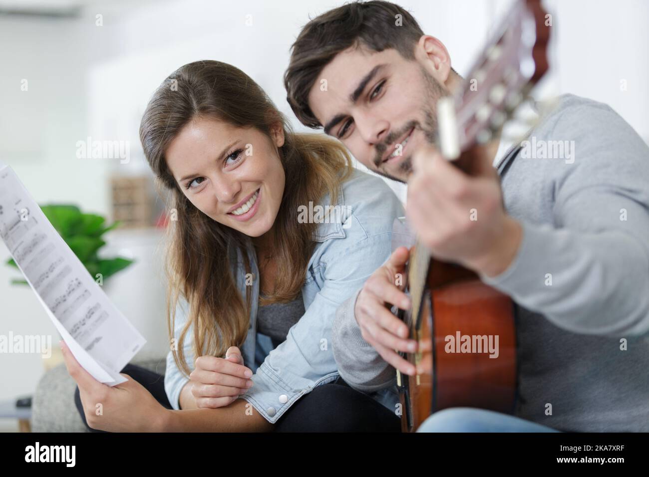 handsome man teaching girlfriend how to play the guitar Stock Photo