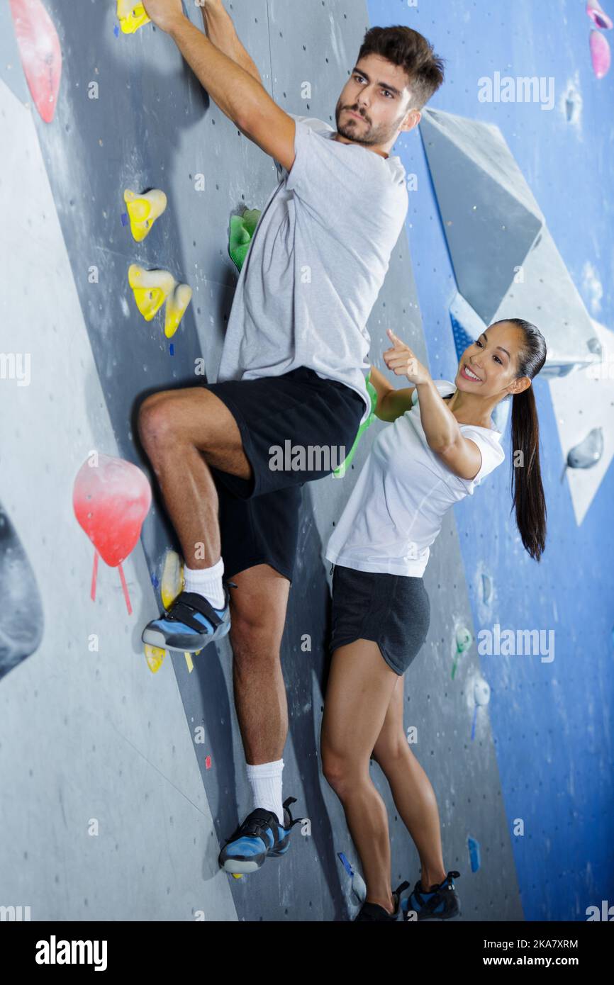 female wall climber pointing at next foothold for client Stock Photo