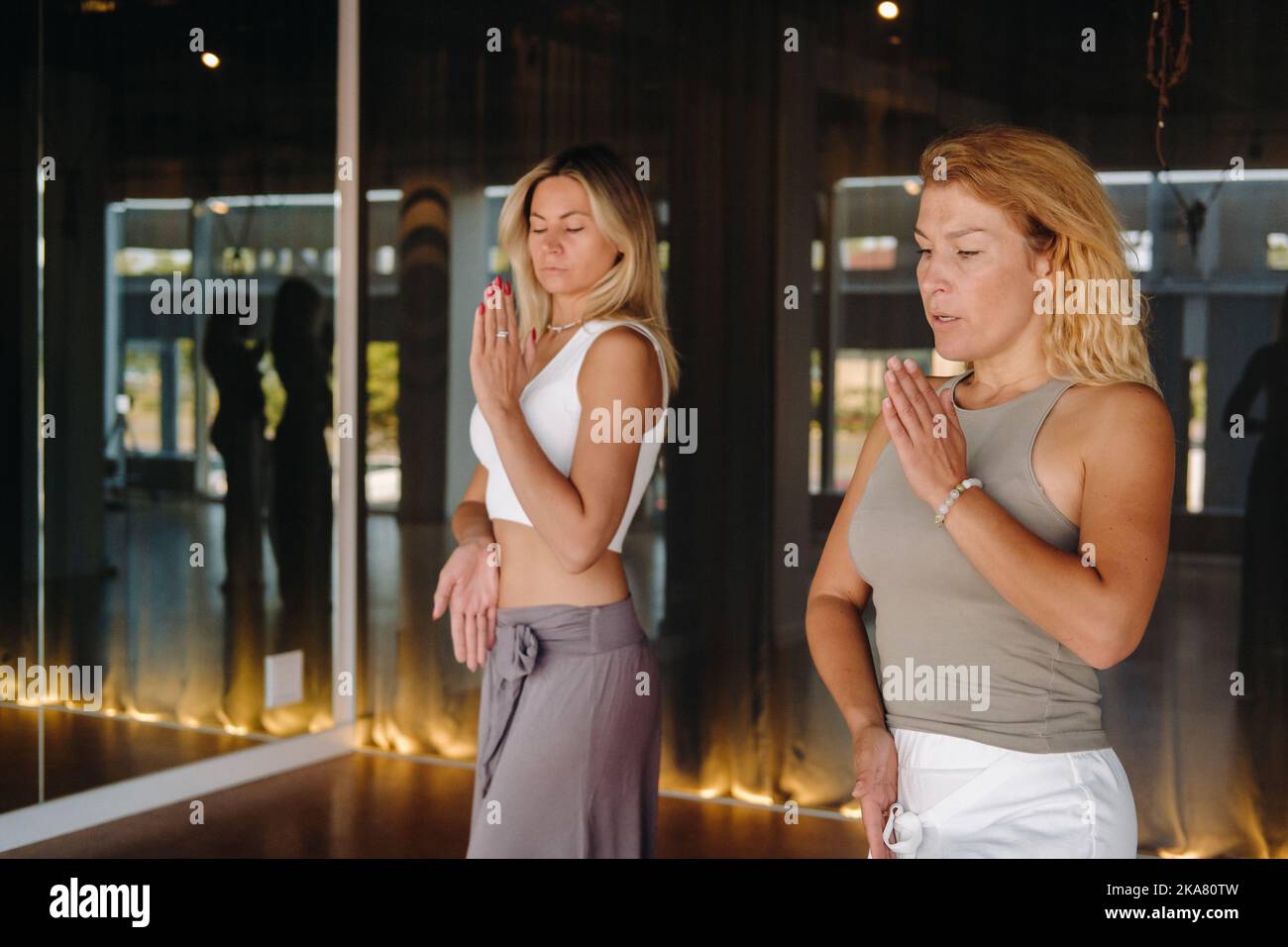 Two beautiful women are doing yoga standing up in the fitness room Stock Photo
