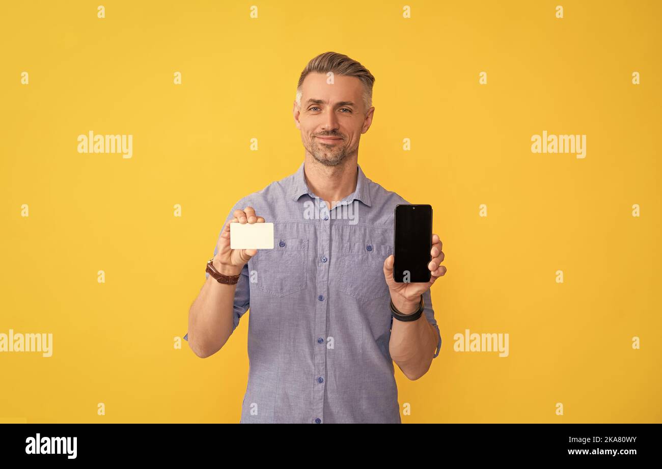 smiling man showing phone and credit card with copy space, internet buy Stock Photo