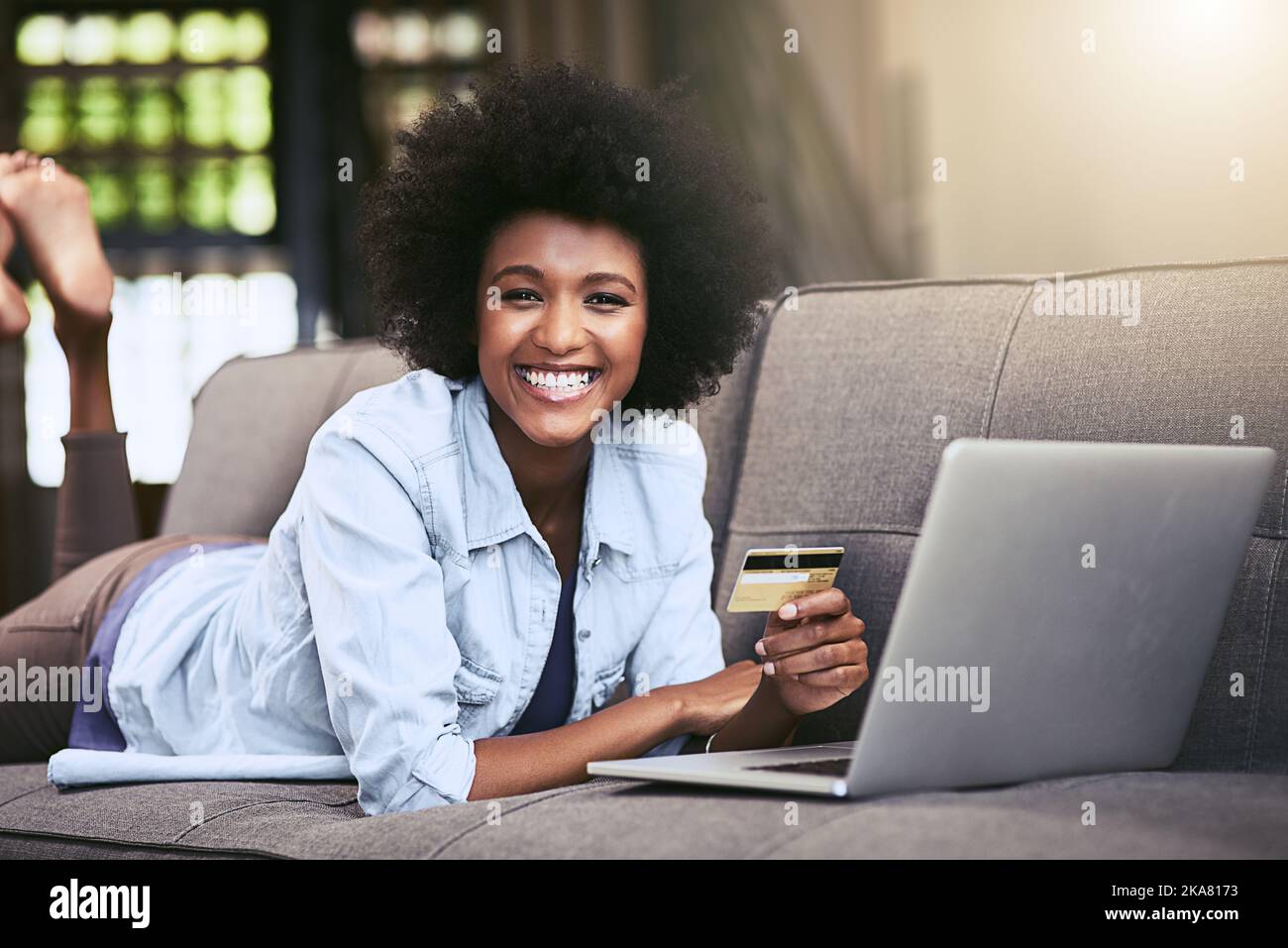 I buy most of my groceries online. a young woman using a laptop and credit card on the sofa at home. Stock Photo