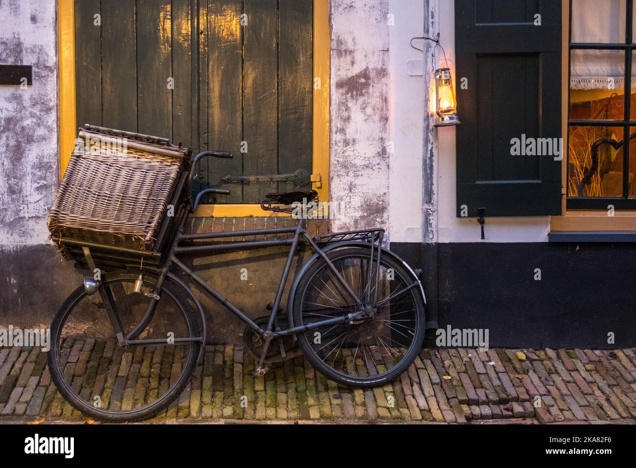 Enkhuizen, Netherlands. October 2022. Old cargo bike and oil lamp against a wall. High quality photo Stock Photo