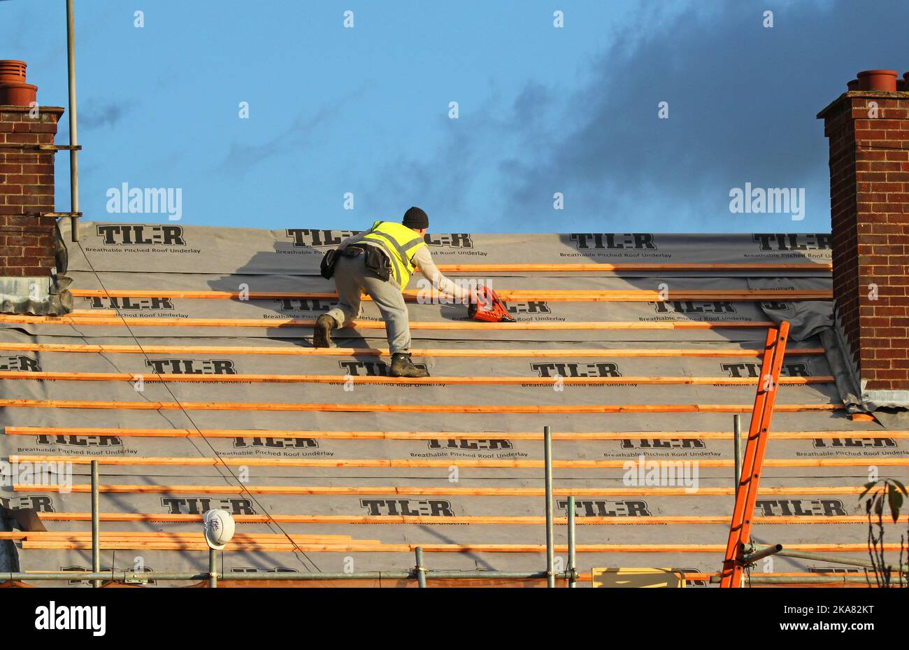 Roofer fixing wooden slats to roof to attach new tiles Stock Photo Alamy