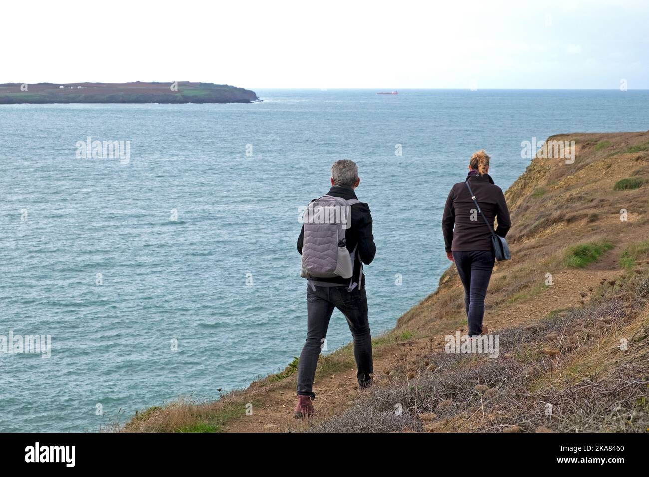 Rear back view of two people couple walking along cliff edge on Wales coast path in autumn Marloes Pembrokeshire UK Great Britain KATHY DEWITT Stock Photo