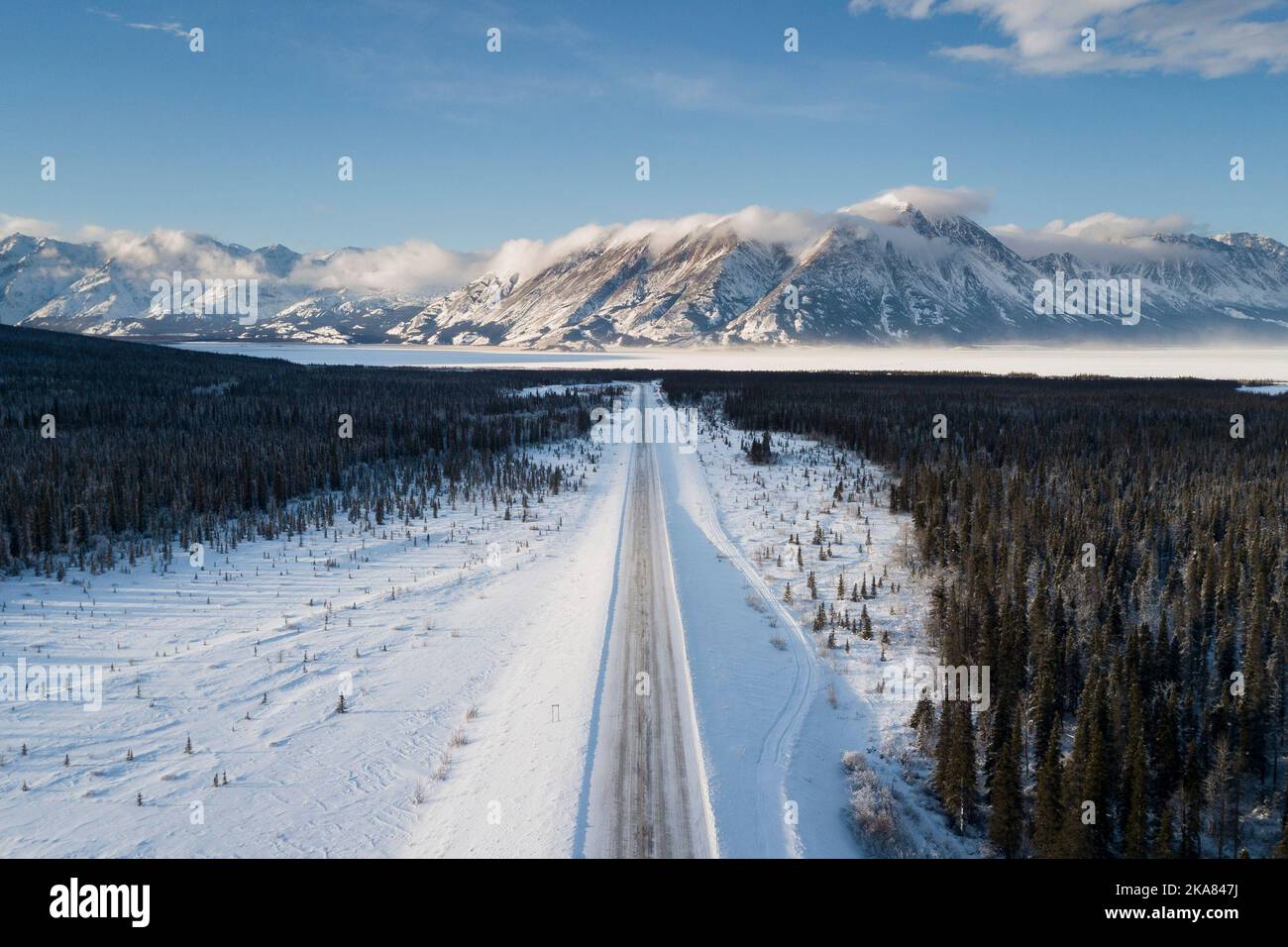 An aerial view of a landscape with mountain ranges and forests covered in snow in Whitehorse