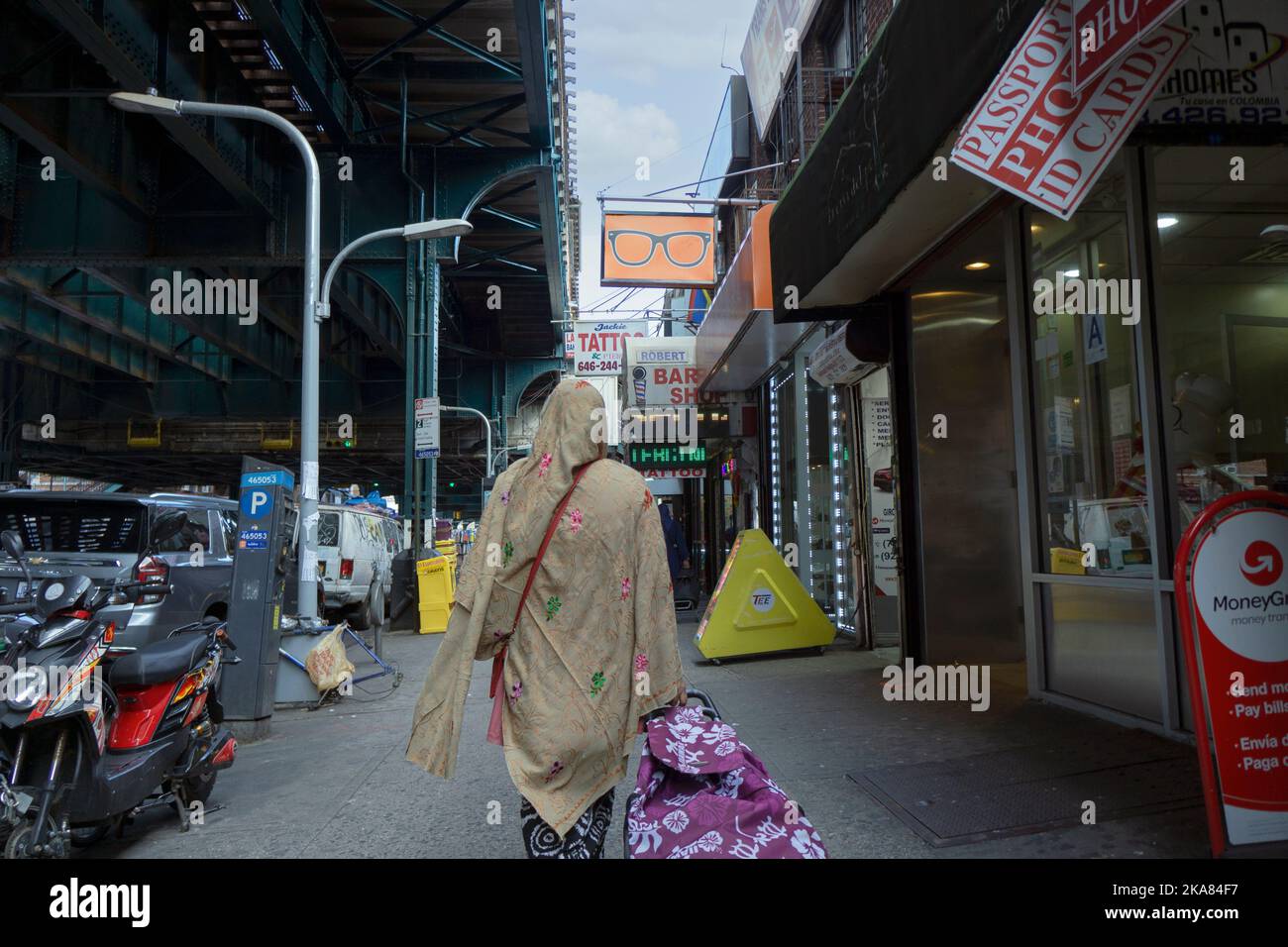 An anonymous Muslim woman photographed from behind walks Eastward on Roosevelt Avenue in Jackson Heights, Queens, New York City Stock Photo