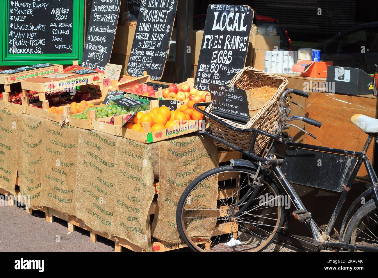 Old delivery bike with basket parked in front of a fruit and vegetable