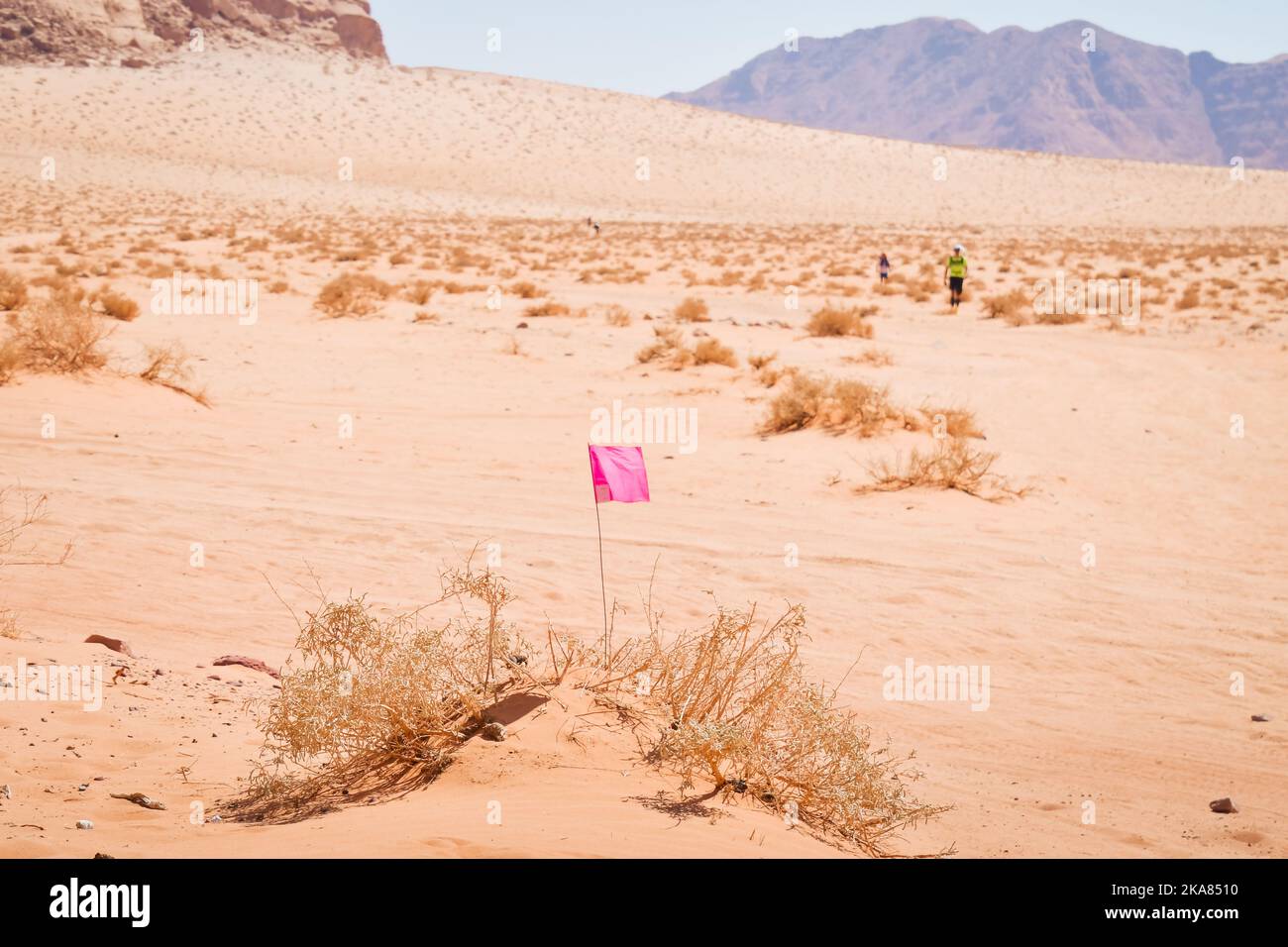 Wadi rum, Jordan - 5th October, 2022: flag and Athlete competitors fast walk in desert pass markings on extreme hot in challenging Ultra X Jordan mult Stock Photo