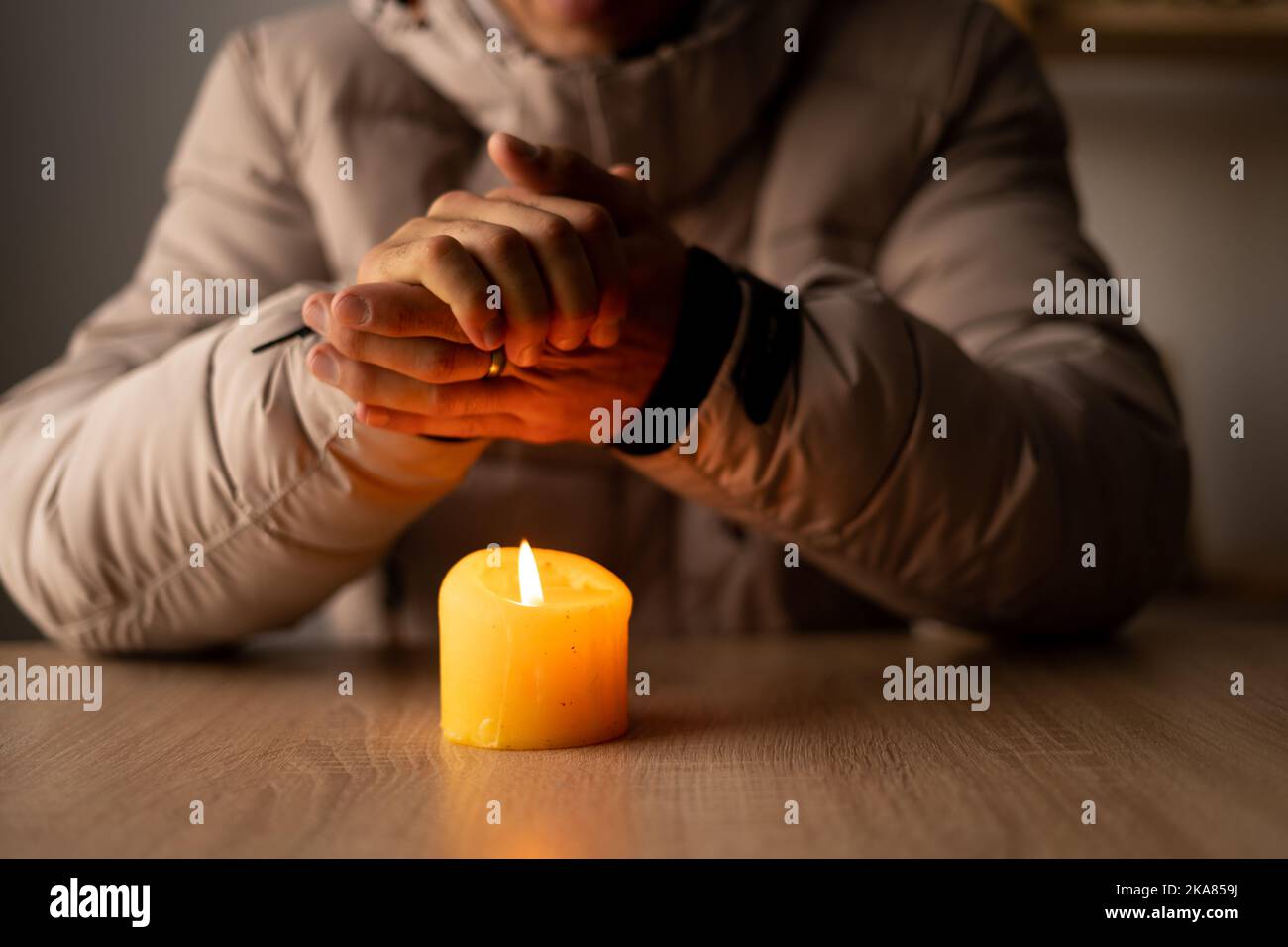 https://c8.alamy.com/comp/2KA859J/shutdown-of-heating-and-electricity-a-man-dressed-in-a-warm-winter-jacket-sits-at-home-at-a-table-and-warms-his-hands-from-a-burning-candle-power-2KA859J.jpg