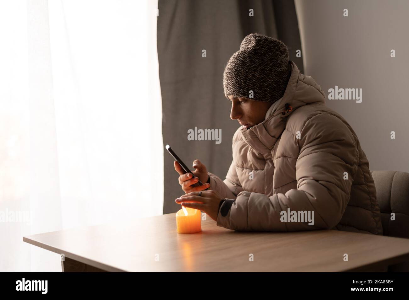 Sick young man feel cold wearing at warm clothes watching movie on smartphone, annoyed guy shiver freezing warming at home wrapped with plaid, problem Stock Photo