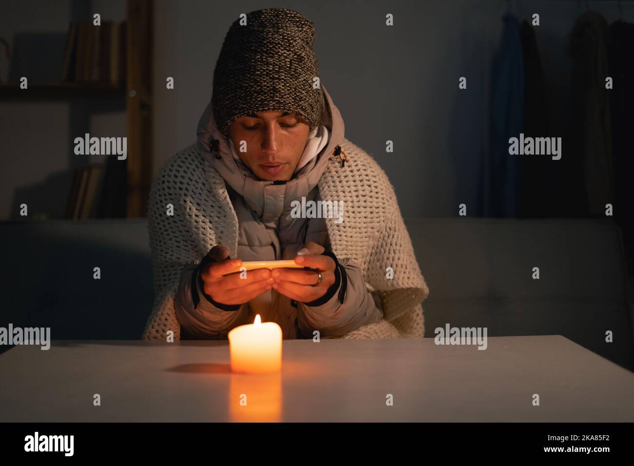 Tired man suffers in no heating and no electricity during an energy crisis in Europe causing blackouts. Stock Photo