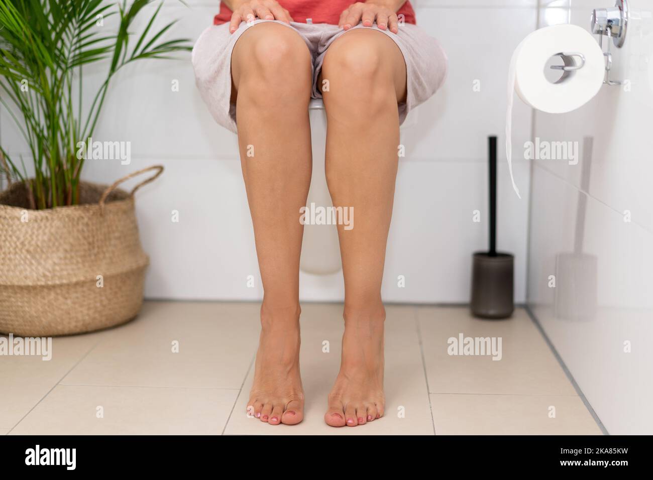 Woman sitting on the toilet. Unhealthy positions for defecation. Stock Photo