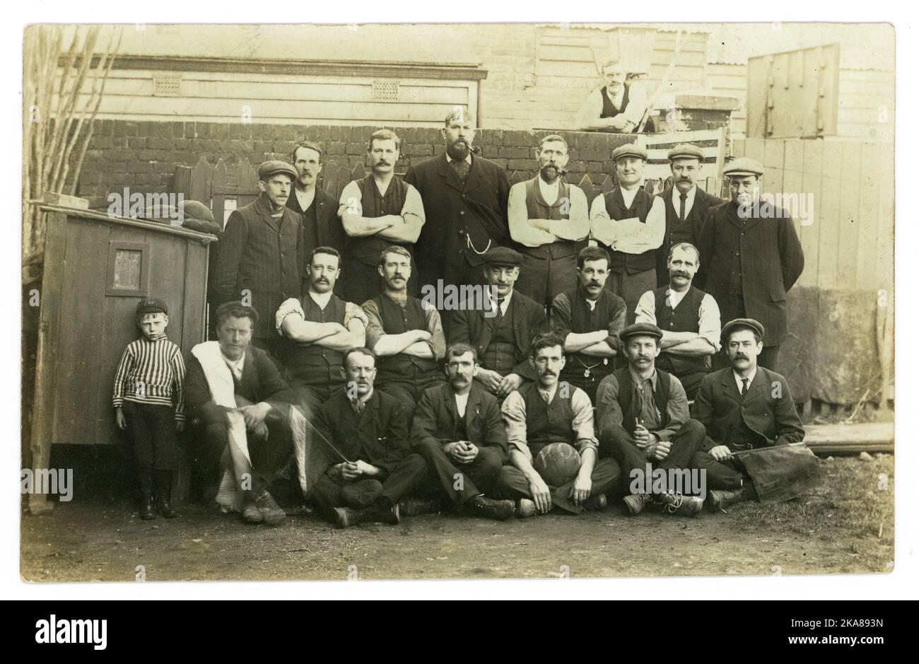 Original early 1920's amateur street football team, lots of characters, neighbours, referees waving flags, big chap at the back maybe manager, in an urban setting, U.K. Stock Photo