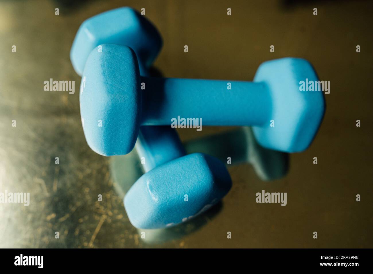 two five pound light blue hand weights on reflective golden surface Stock Photo