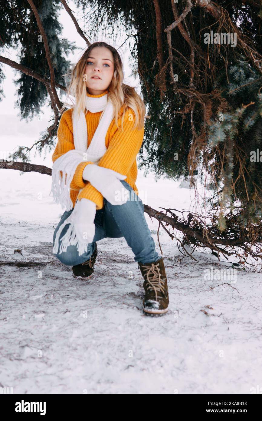 Teen blonde in a yellow sweater outside in winter. A teenage girl on a walk in winter clothes in