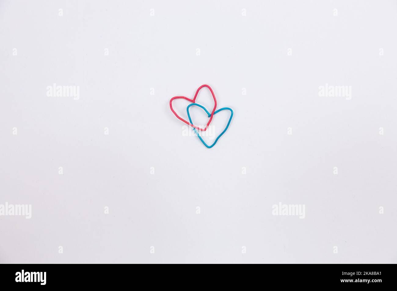 A blue and red paper clip in the shape of a heart on isolated white