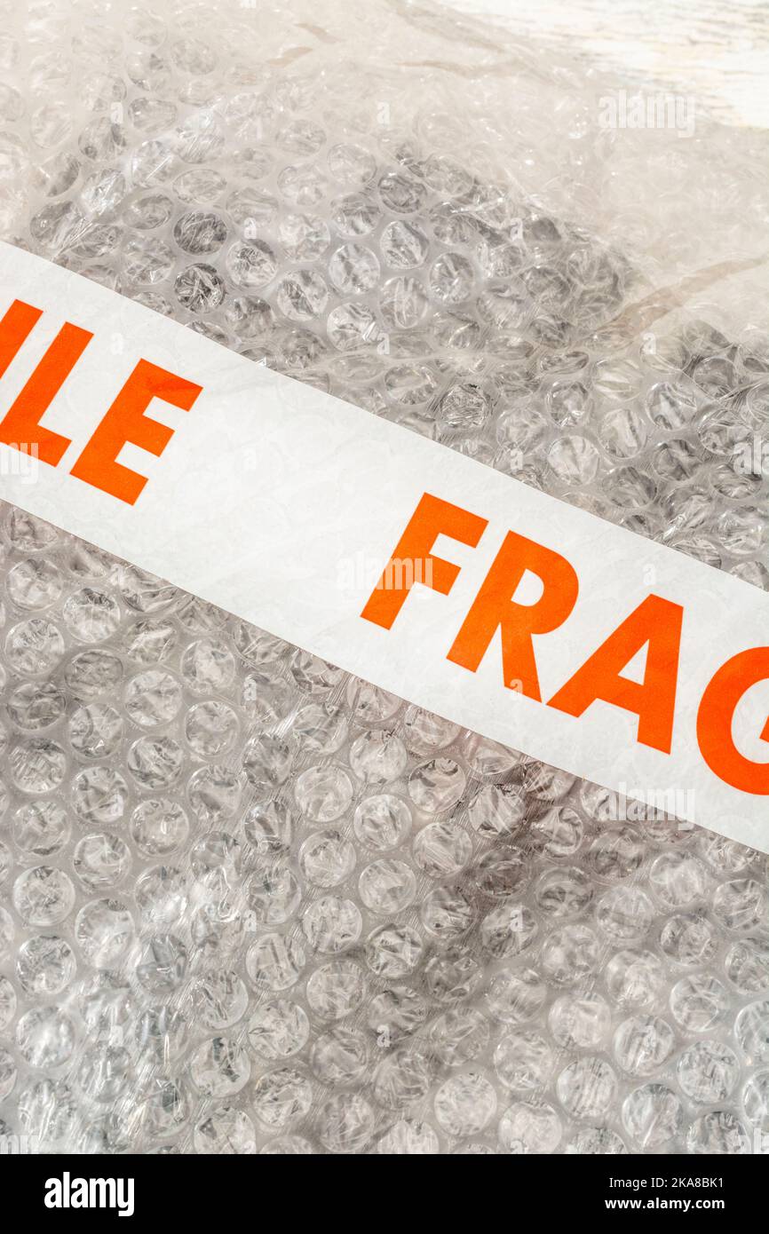 'Fragile' sticky tape labelling on plastic padded packing material or sheet containing the